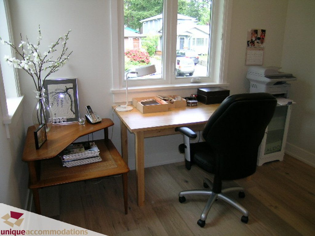 Spacious home office with wooden desk, ergonomic chair, and city view through large windows. - 2015 Lloyd Avenue, North Vancouver