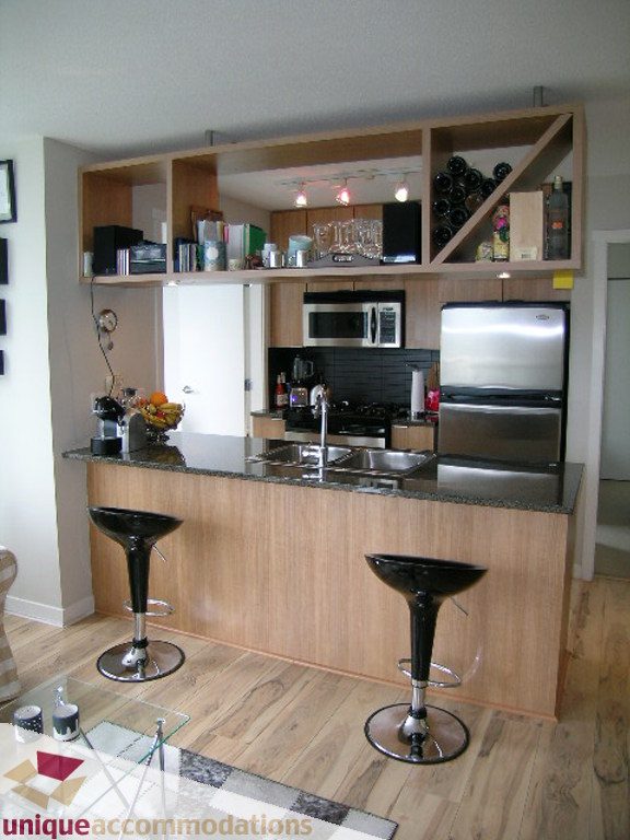 Bright kitchen with wooden cabinets, granite countertops, and hardwood floors. - 707 - 1010 Richards Street, Vancouver Downtown