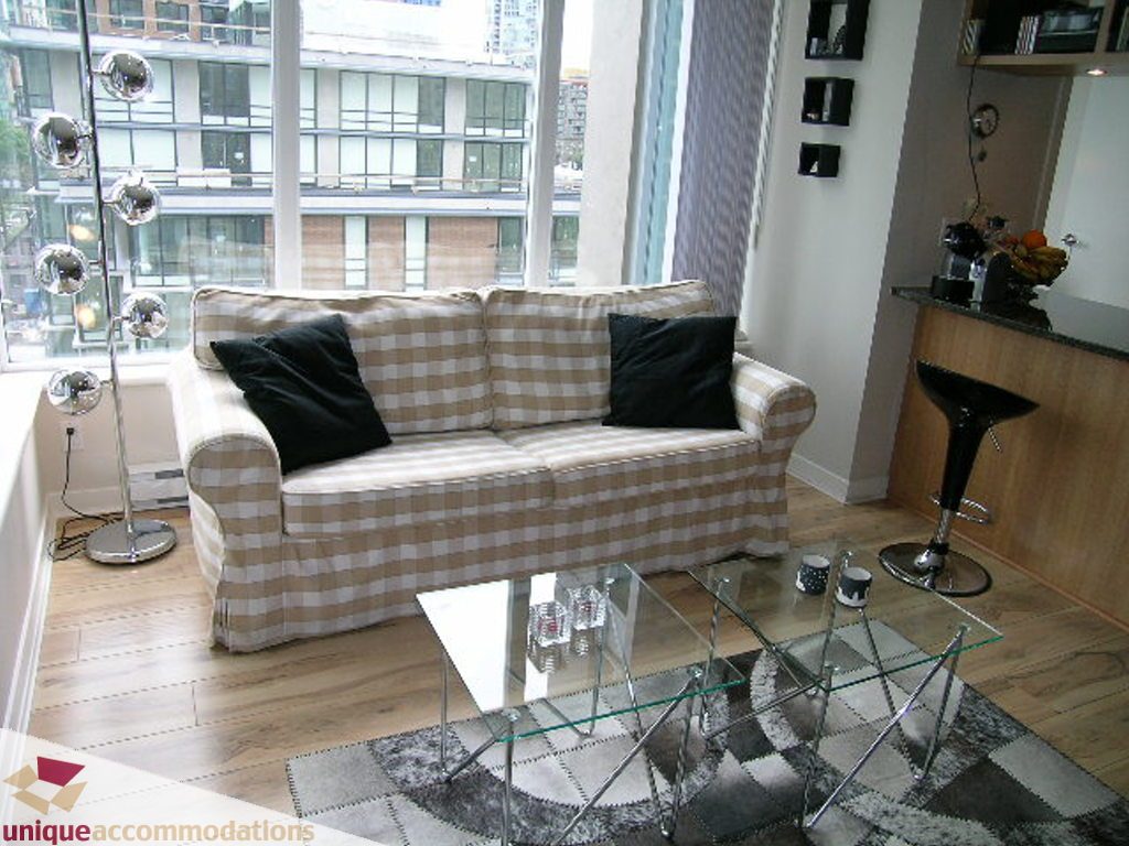Bright living room with city view, hardwood floors, and a checkered sofa. - 707 - 1010 Richards Street, Vancouver Downtown