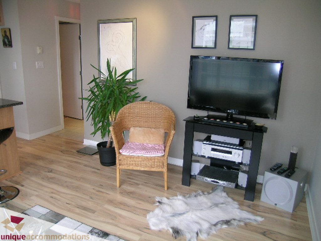 Bright living room with hardwood floors, a flat-screen TV, and a cozy seating area. - 707 - 1010 Richards Street, Vancouver Downtown