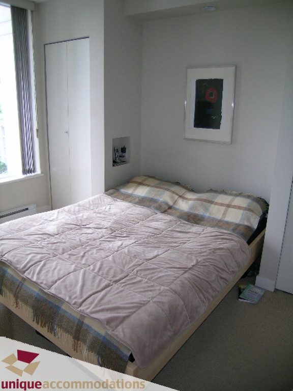 Bright bedroom with a double bed, plaid bedding, and a framed abstract art piece on the wall. - 707 - 1010 Richards Street, Vancouver Downtown