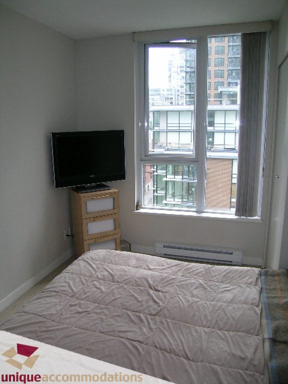 Bright bedroom with city view and wooden bed frame. - 707 - 1010 Richards Street, Vancouver Downtown