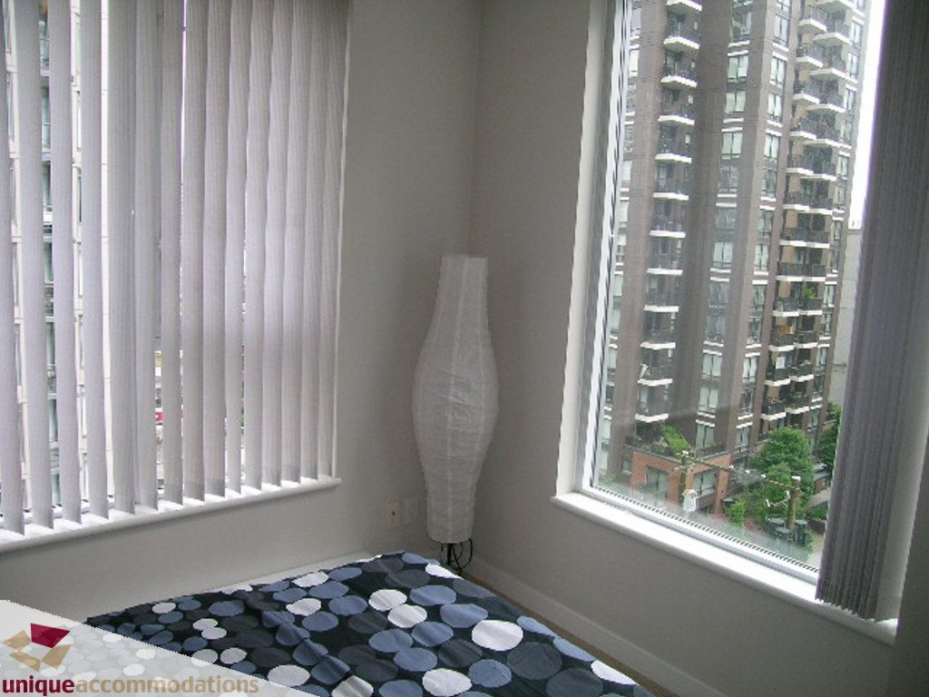 Bright bedroom with city view and patterned bedding. - 707 - 1010 Richards Street, Vancouver Downtown