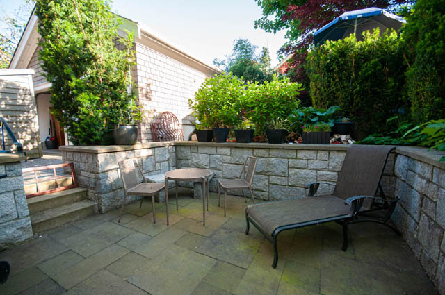 Outdoor patio with stone walls and lounge chair surrounded by lush greenery. - 2447 West 6th Ave., Vancouver West Side