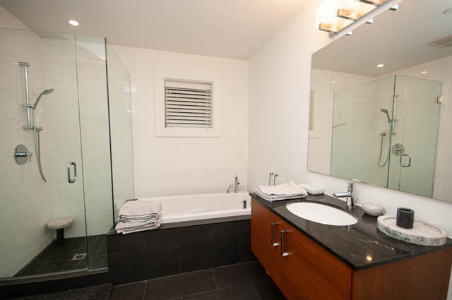 Modern bathroom with glass shower enclosure and dark granite vanity. - 2447 West 6th Ave., Vancouver West Side