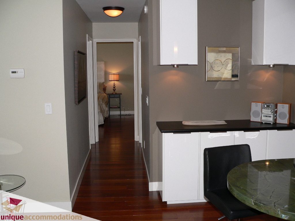 Bright kitchen with white cabinets, dark hardwood floors, and a green marble table. - 203 - 1066 W 13th Ave, Vancouver West Side