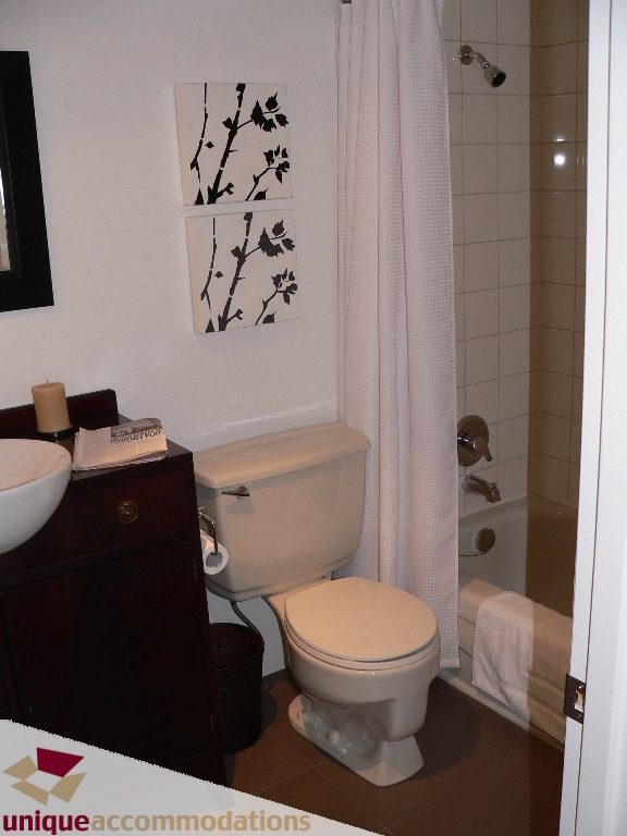 Bathroom with white toilet, sink, and black-and-white art on wall. - 203 - 1066 W 13th Ave, Vancouver West Side