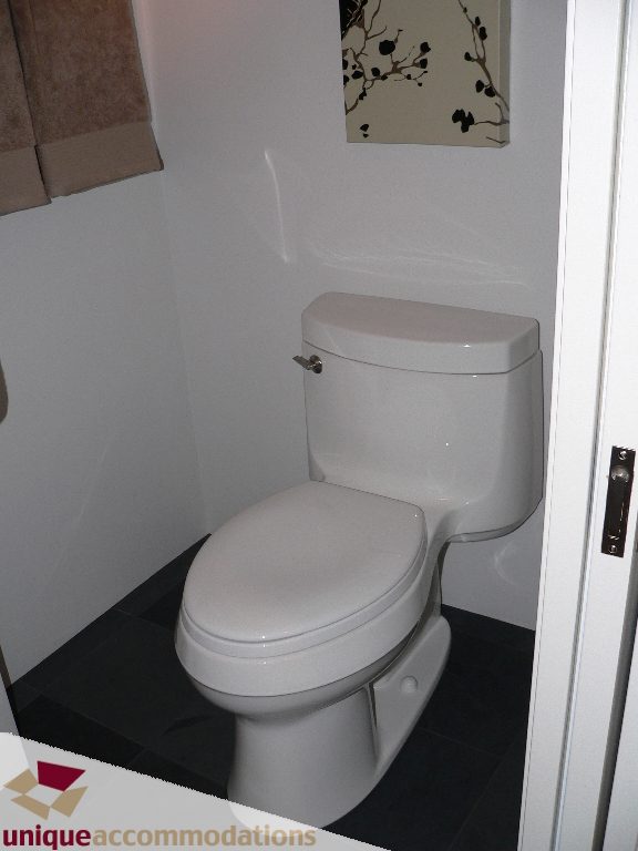 Bathroom with white toilet and black tiled floor. - 203 - 1066 W 13th Ave, Vancouver West Side