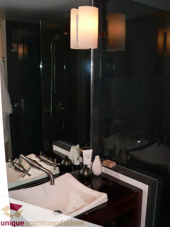 Furnished bathroom with modern sink, dark countertop, and sleek lighting fixtures. - 203 - 1066 W 13th Ave, Vancouver West Side