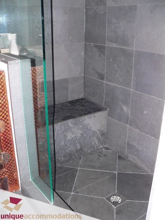 Bathroom with glass shower, dark gray tiles, and built-in bench. - 203 - 1066 W 13th Ave, Vancouver West Side