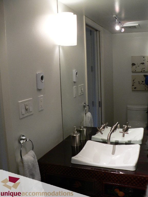 Modern bathroom with dark countertop and wall-mounted light fixture. - 203 - 1066 W 13th Ave, Vancouver West Side