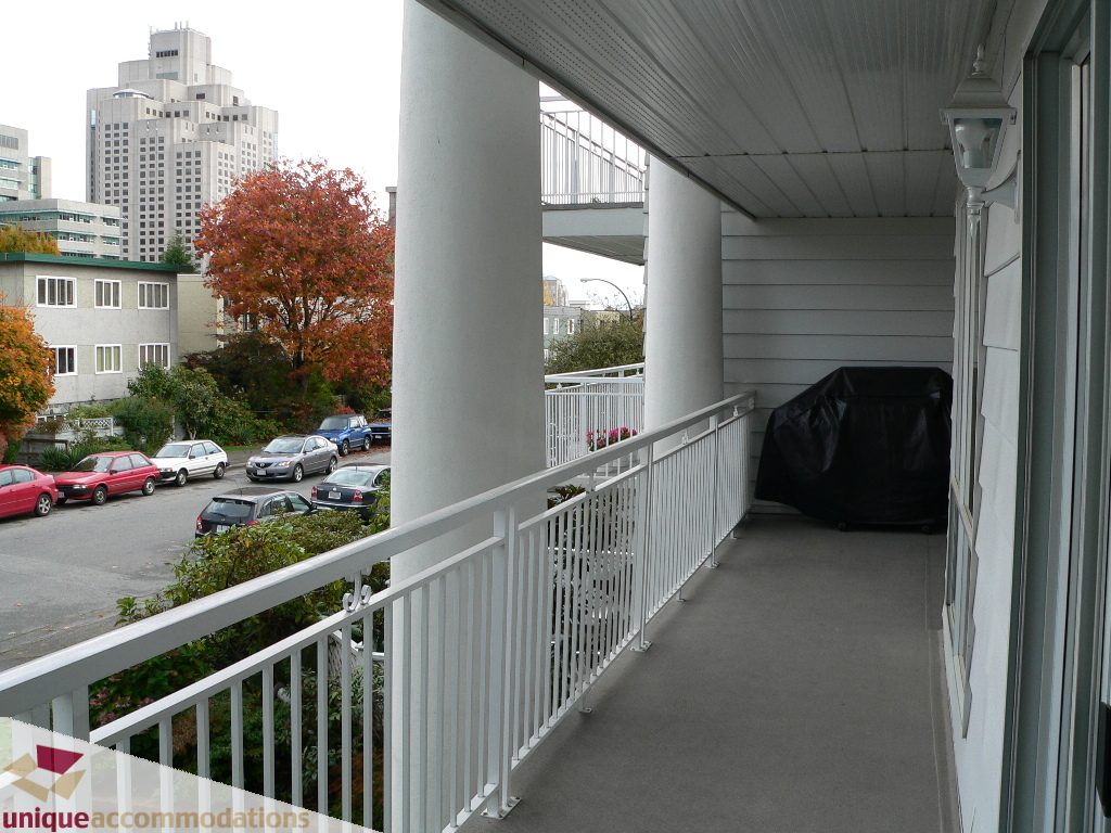 Furnished balcony with white railings, city view, and autumn foliage. - 203 - 1066 W 13th Ave, Vancouver West Side