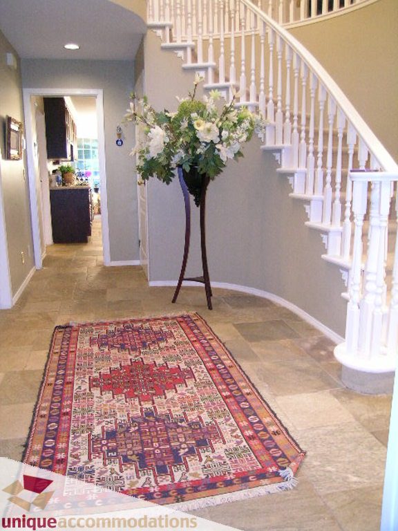 Foyer with tiled floor, staircase, and large floral arrangement. - 5735 Nancy Green way, North Vancouver