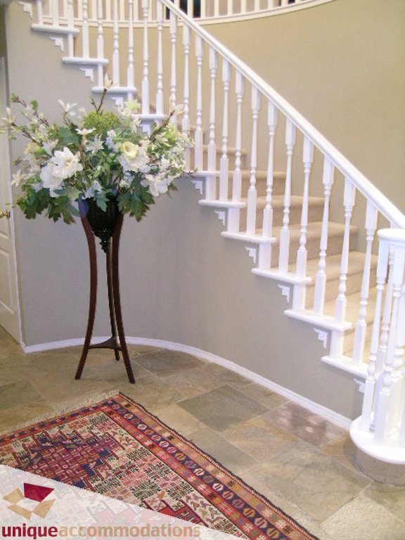 Staircase with white banister and floral arrangement in vase on landing. - 5735 Nancy Green way, North Vancouver