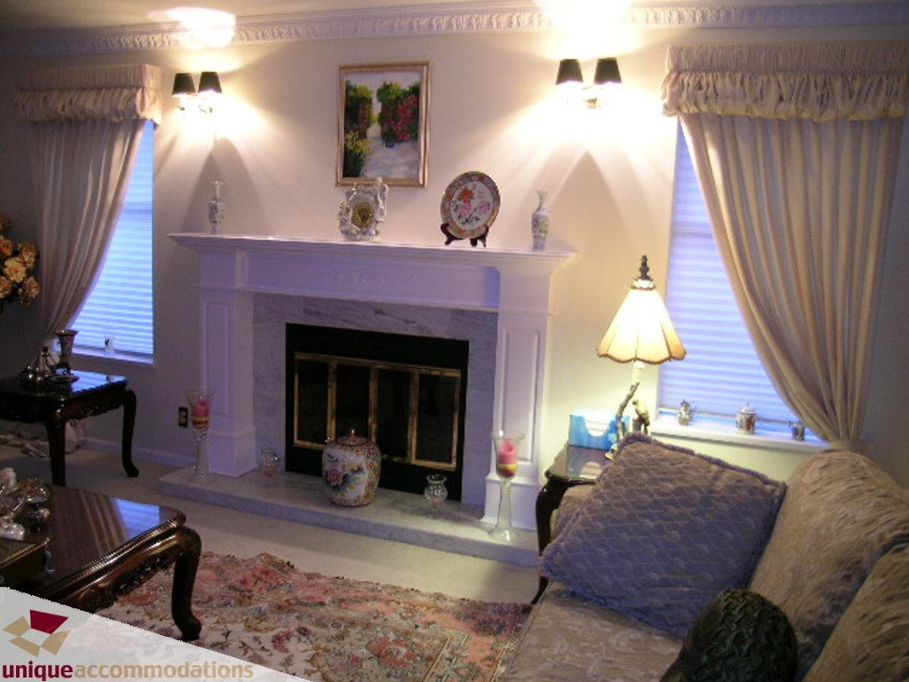 Furnished living room with elegant fireplace, floral rug, and cozy seating. - 5735 Nancy Green way, North Vancouver