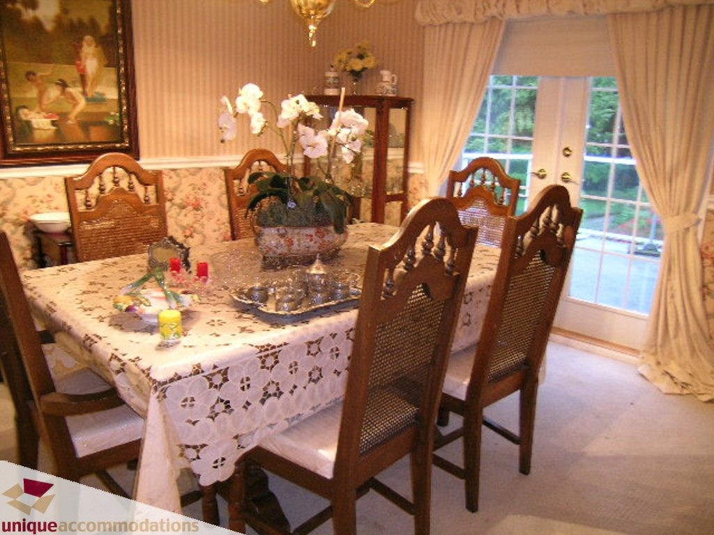 Formal dining room with ornate chairs and floral tablecloth, large window with curtains. - 5735 Nancy Green way, North Vancouver