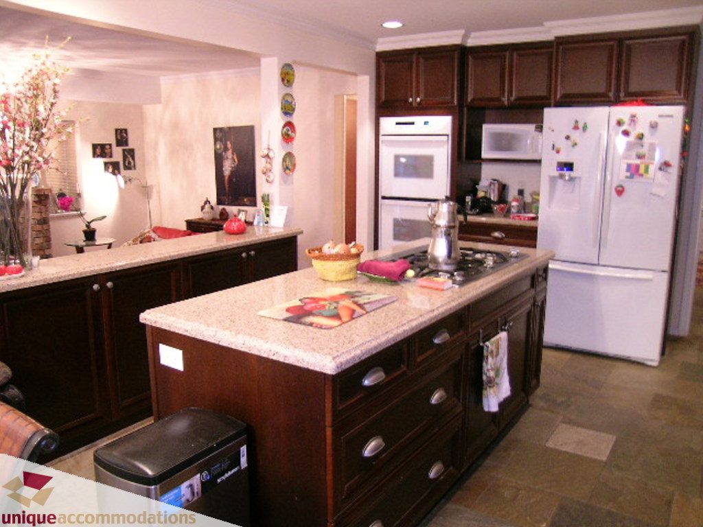 Bright kitchen with granite countertops, dark wood cabinets, and a modern refrigerator. - 5735 Nancy Green way, North Vancouver