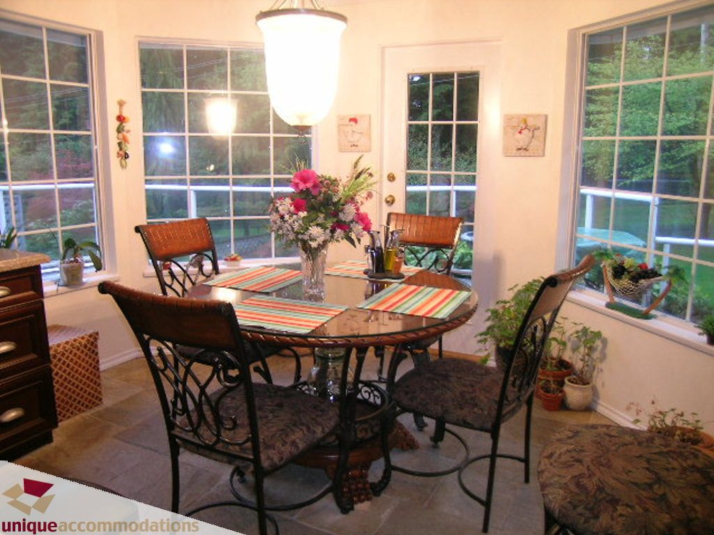 Bright dining area with glass table, floral centerpiece, and large windows. - 5735 Nancy Green way, North Vancouver