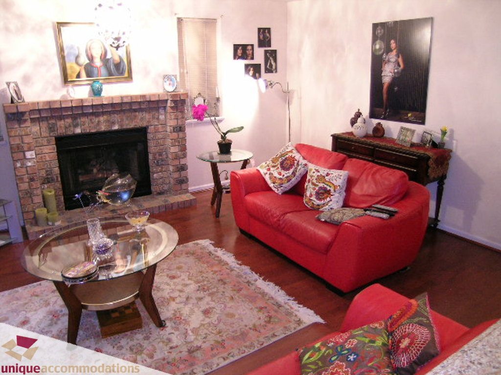 Furnished living room with red sofas, brick fireplace, and patterned rug. - 5735 Nancy Green way, North Vancouver