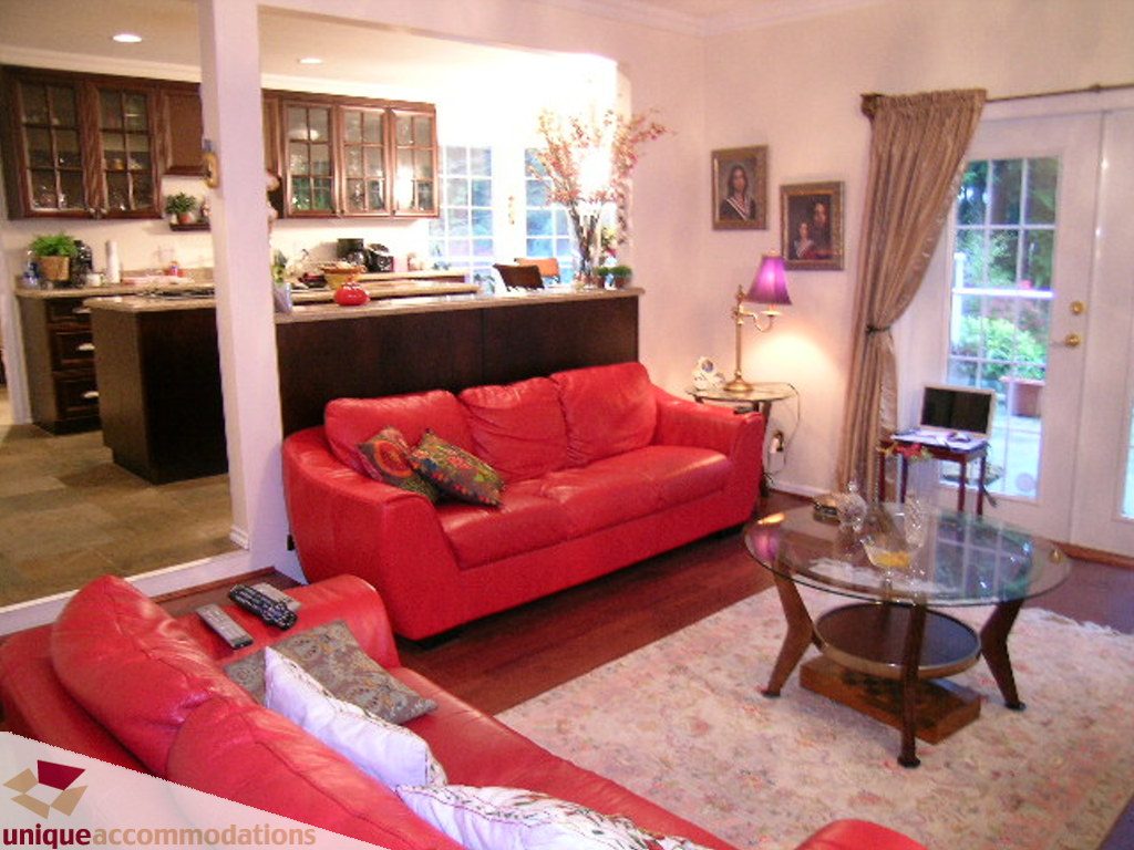 Furnished living room with red leather couches, hardwood floors, and a glass coffee table. - 5735 Nancy Green way, North Vancouver