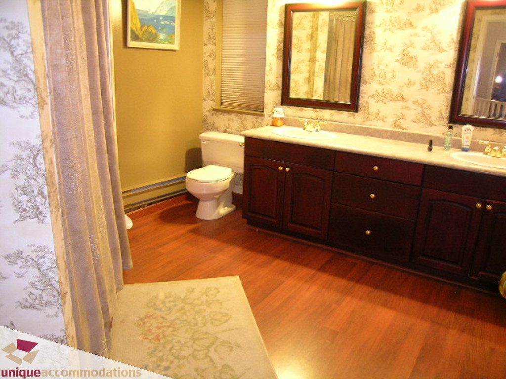 Furnished bathroom with wooden floors, dark cabinets, and a large mirror. - 5735 Nancy Green way, North Vancouver