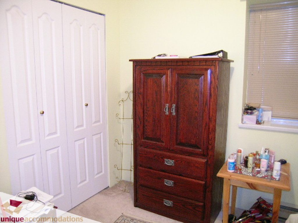 Bright bedroom with wooden armoire and white closet doors. - 5735 Nancy Green way, North Vancouver