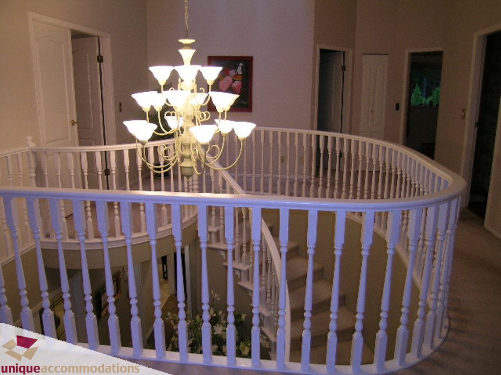 Staircase with white railing and chandelier, leading to upper level. - 5735 Nancy Green way, North Vancouver