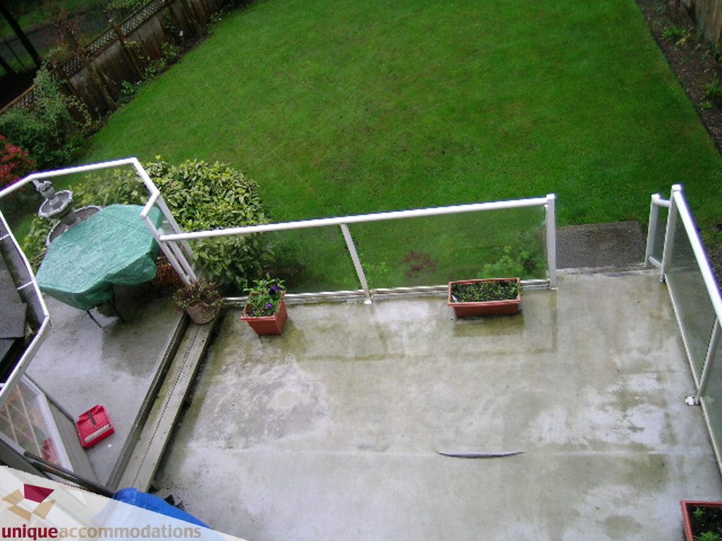 Spacious patio with green lawn and potted plants. - 5735 Nancy Green way, North Vancouver