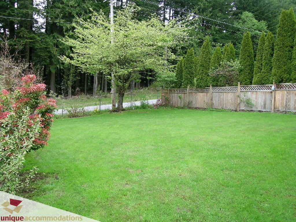 Lush green backyard with neatly trimmed grass and a wooden fence. - 5735 Nancy Green way, North Vancouver
