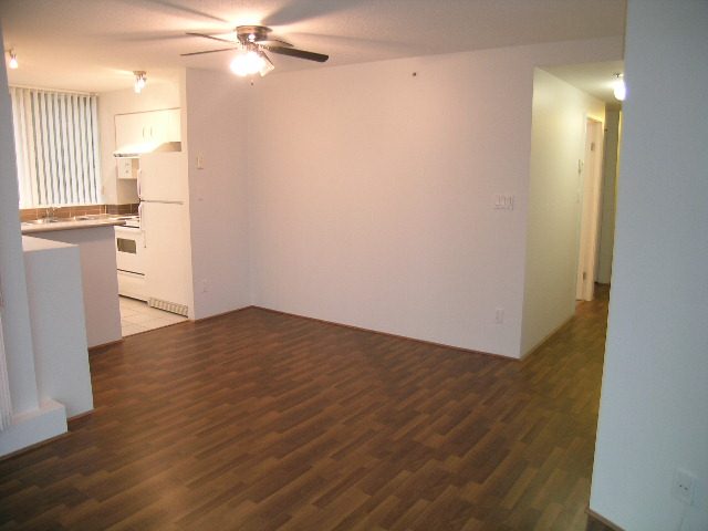 Bright kitchen with white cabinets and hardwood floors, leading to a spacious living area. - 2006 - 588 Broughton St, Vancouver Downtown