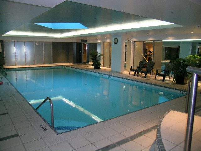 Spacious, modern 1-bedroom + den with a large, well-lit indoor pool area featuring a sleek design and ambient lighting.