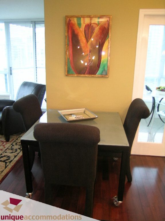 Furnished dining area with hardwood floors, city view, and vibrant artwork. - 2907 - 1328 W Pender St, Vancouver Downtown