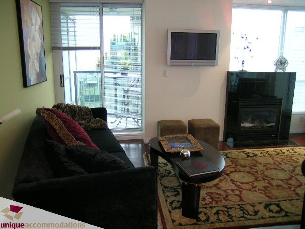 Furnished living room with city view, hardwood floors, and a large flat-screen TV. - 2907 - 1328 W Pender St, Vancouver Downtown