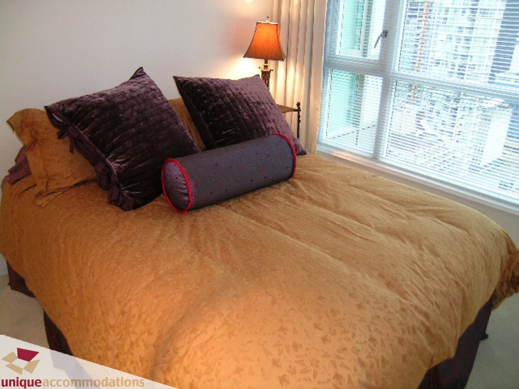 Furnished bedroom with plush bedding and large window view. - 2907 - 1328 W Pender St, Vancouver Downtown