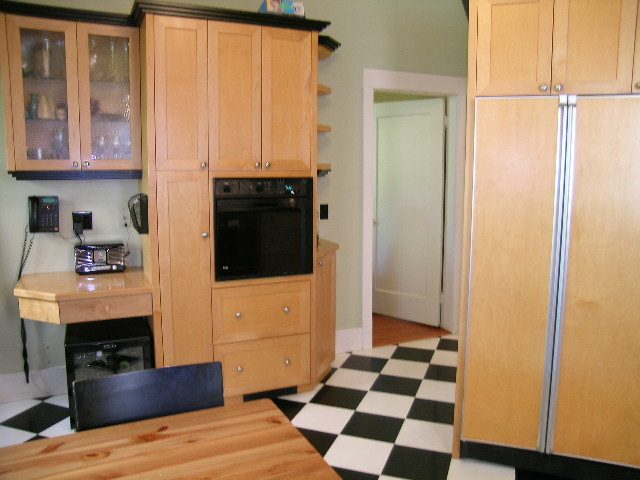Bright kitchen with wooden cabinets, black and white checkered floor, and a small breakfast nook. - 3602 Fromme Rd, North Vancouver