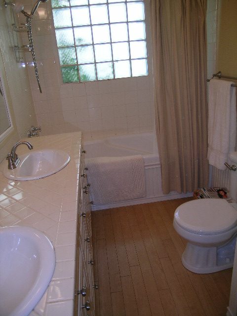 Bright bathroom with white sink, bathtub, and hardwood floors. - 3602 Fromme Rd, North Vancouver