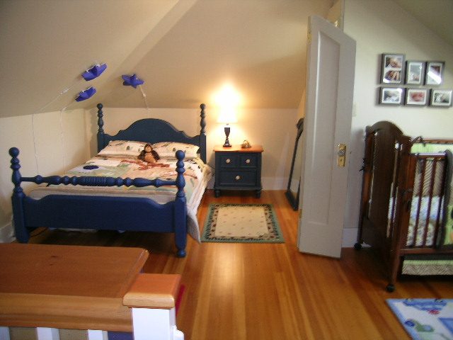 Bright bedroom with hardwood floors, blue bed, and lamp. - 3602 Fromme Rd, North Vancouver