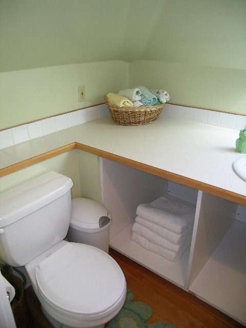 Bathroom with white countertop, wicker basket, and neatly folded towels. - 3602 Fromme Rd, North Vancouver