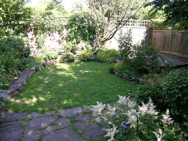 Spacious backyard with stone path, grassy area, and lush greenery. - 3602 Fromme Rd, North Vancouver
