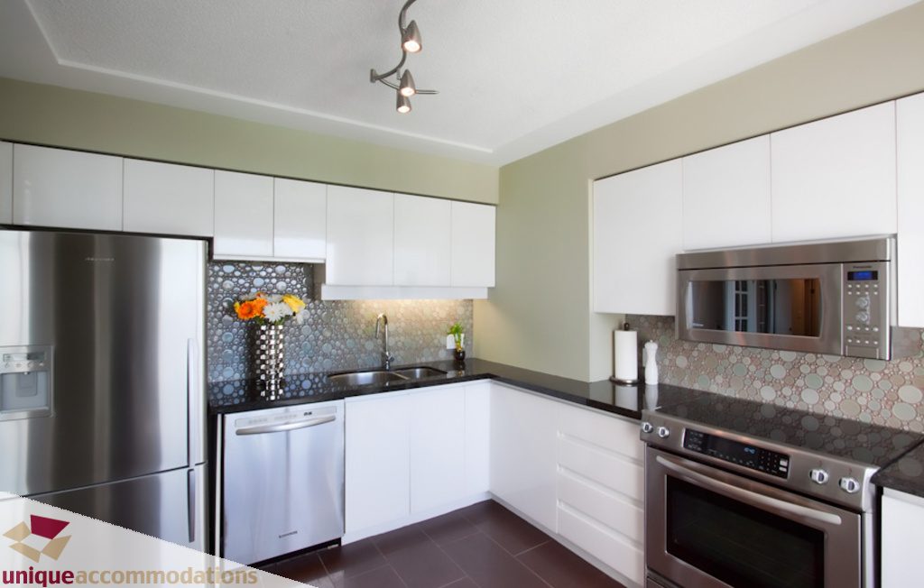 Bright kitchen with stainless steel appliances, white cabinets, and patterned backsplash. - 1806 - 1500 Howe St, Vancouver Downtown