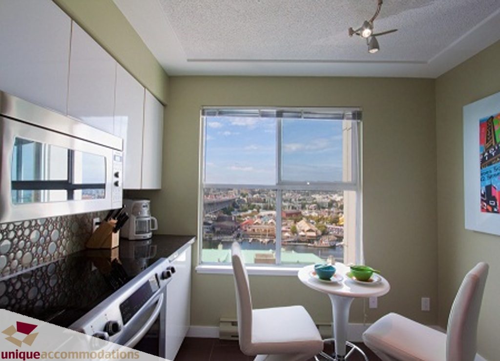 Bright kitchen with modern appliances and a city view through large windows. - 1806 - 1500 Howe St, Vancouver Downtown