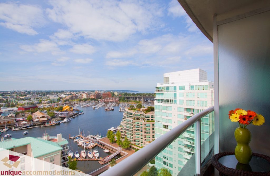 Balcony with city view, boats docked, modern furnishings, and a vase of flowers. - 1806 - 1500 Howe St, Vancouver Downtown