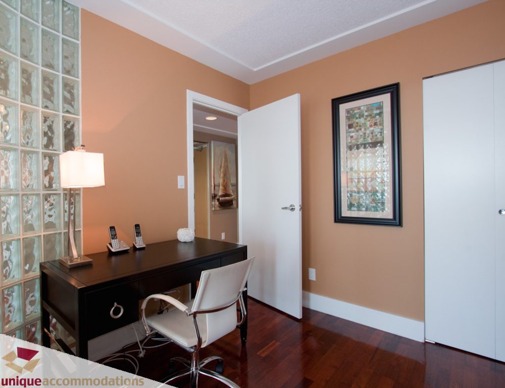 Furnished office with dark wood desk, white chair, and hardwood floors. - 1806 - 1500 Howe St, Vancouver Downtown