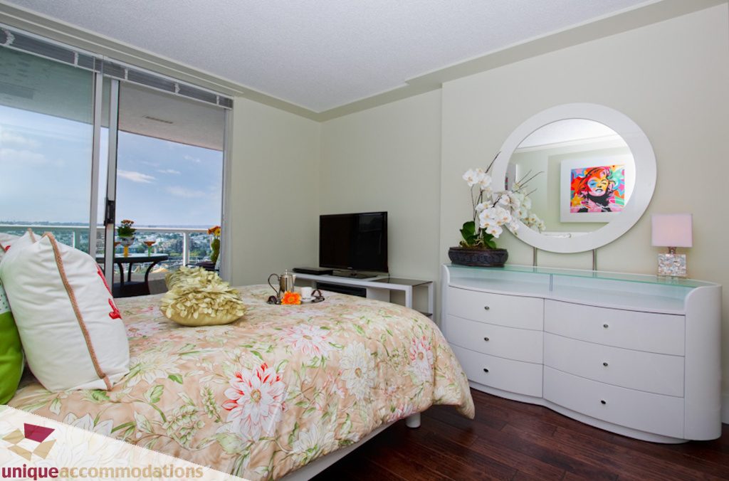 Bright bedroom with city view, floral bedding, and modern white furniture. - 1806 - 1500 Howe St, Vancouver Downtown