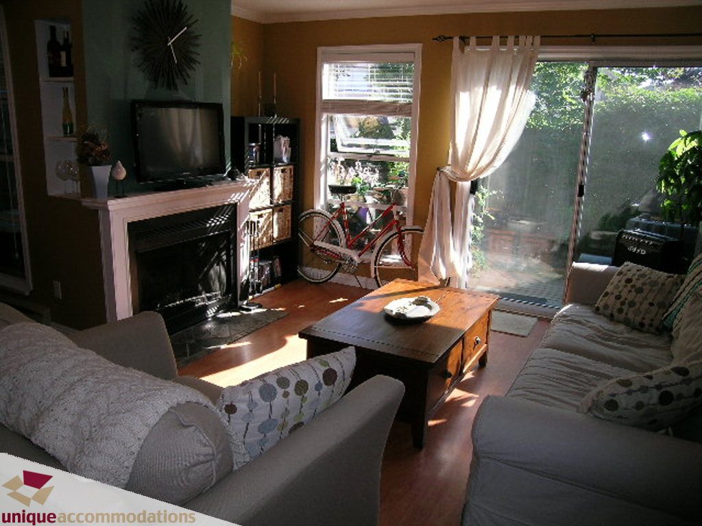 Living room with hardwood floors, large windows, and a cozy sofa setup. - 50 - 900 West 17th, North Vancouver