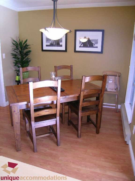 Furnished dining area with wooden table, chairs, and framed artwork on the wall. - 50 - 900 West 17th, North Vancouver