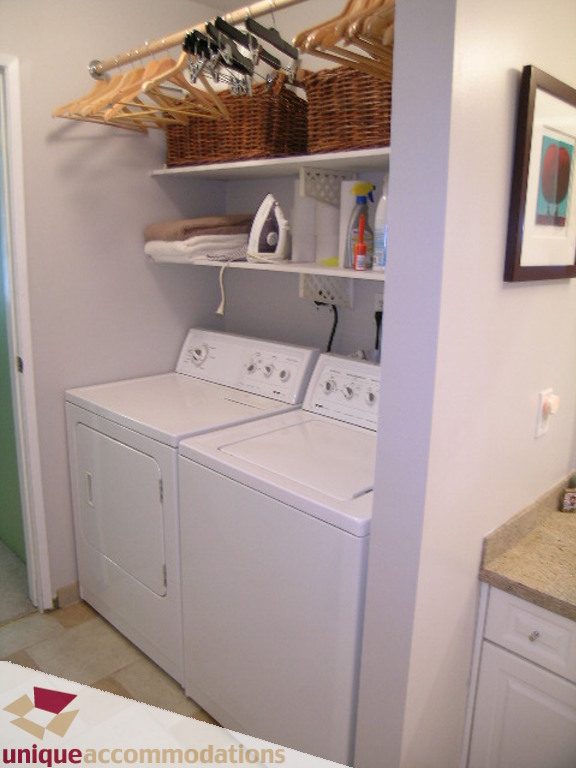 Bright laundry room with white appliances, countertop, and neatly organized shelves. - 50 - 900 West 17th, North Vancouver
