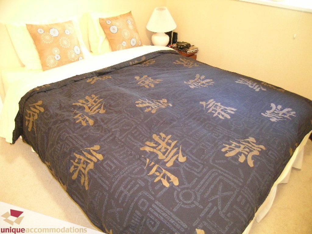 Furnished bedroom with blue patterned blanket and orange pillows. - 50 - 900 West 17th, North Vancouver