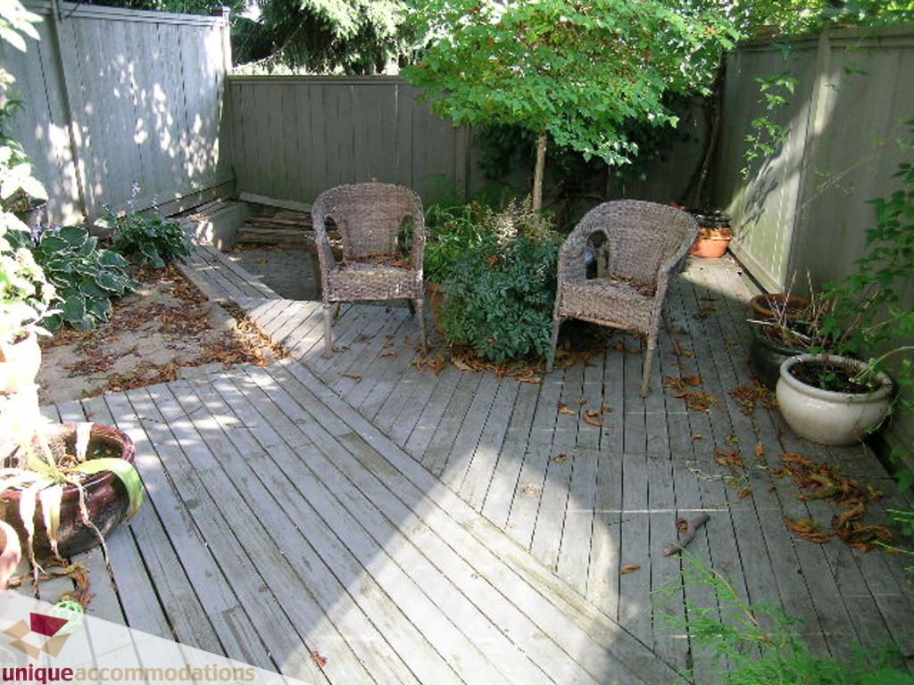 Furnished patio with wooden deck, wicker chairs, and potted plants. - 50 - 900 West 17th, North Vancouver