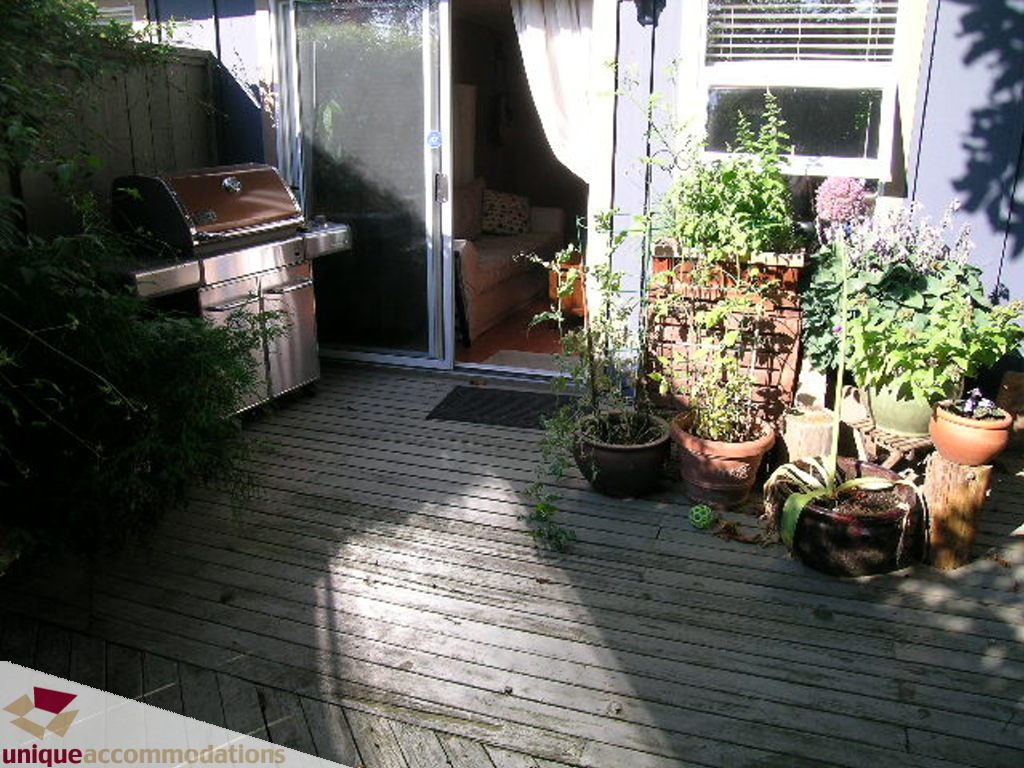 Furnished patio with wooden deck, outdoor grill, and potted plants. - 50 - 900 West 17th, North Vancouver